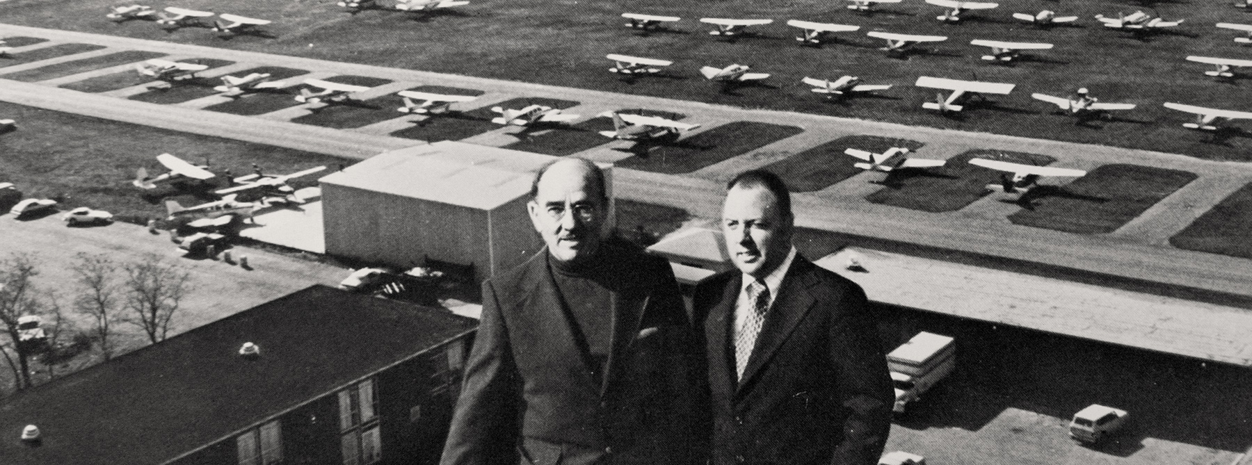 Two men in suits standing outside of an airport